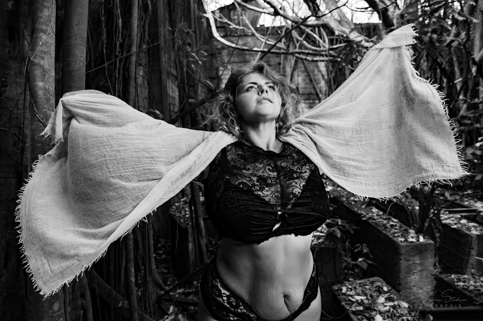 photo noire et blanc d'une jeune femme les bras ouvert dans la nature regardant le ciel